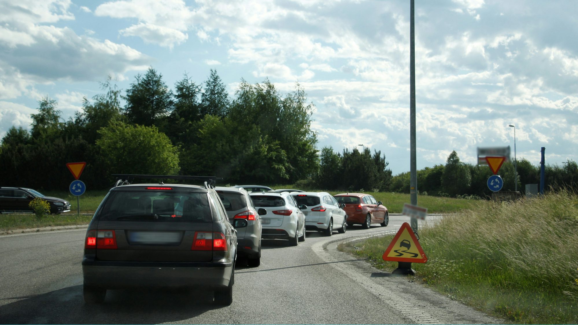 Flera bilar som väntar på att få köra in i en cirkulationsplats.