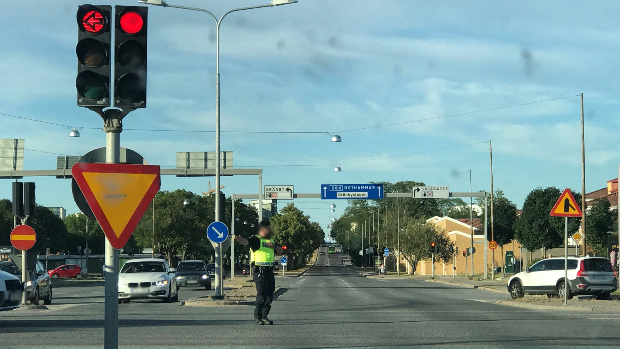 Polis som står och dirigerar trafik i en trafikerad korsning.
