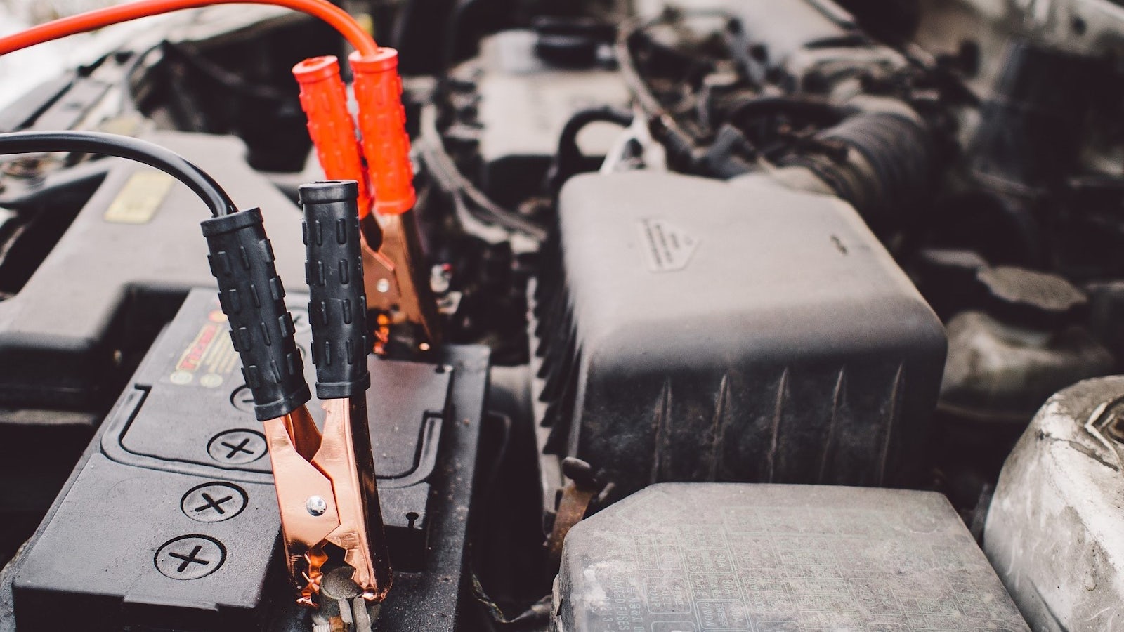 Startkablar kopplade på ett bilbatteri.